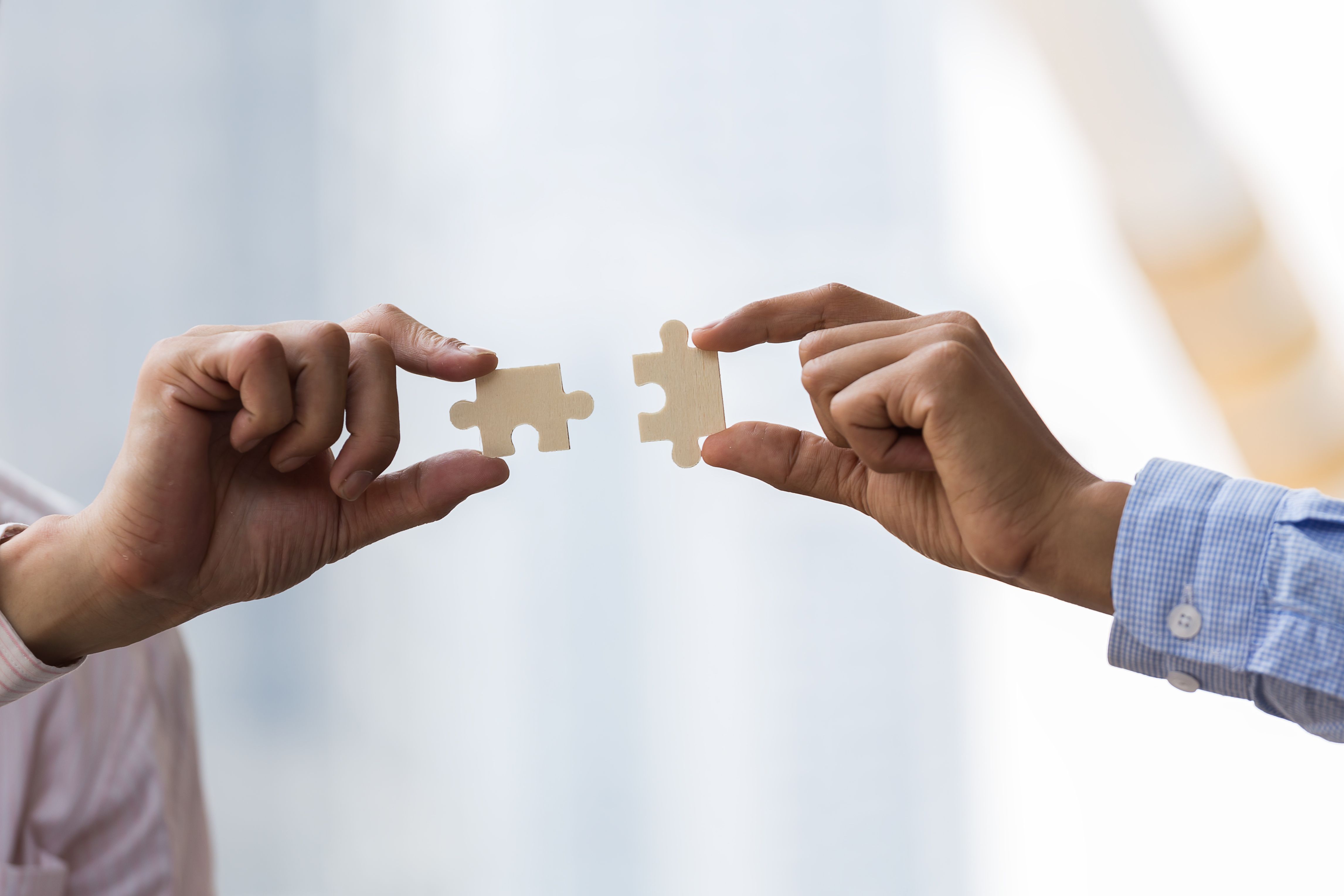 Two people holding jigsaw puzzles pieces